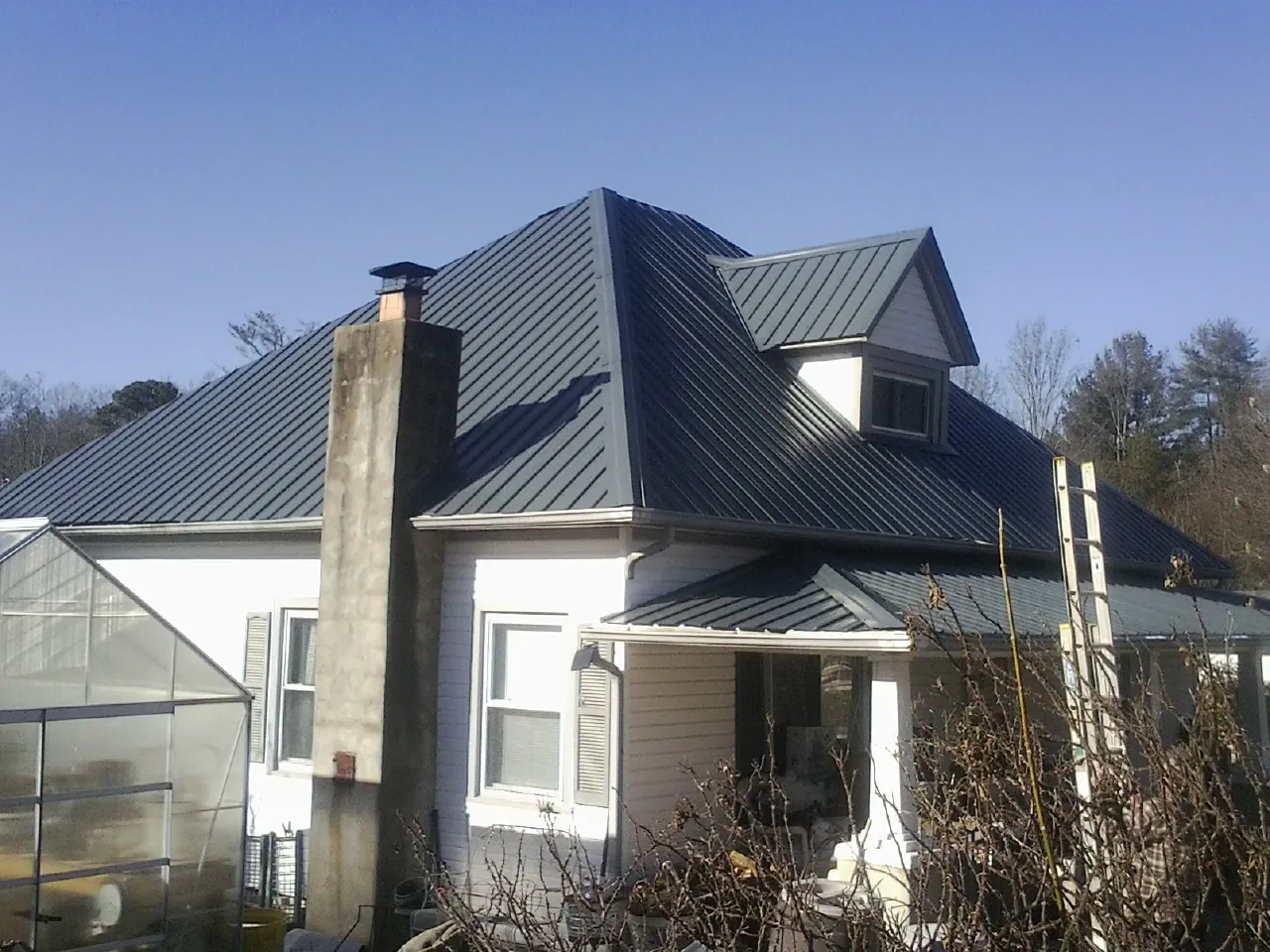 Dark blue standing seam metal roof on a white farmhouse with dormer — Slate & Tile Roof Repair by Roofing Brothers in Perry Point