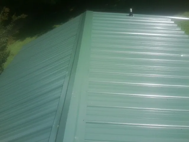 New green metal panels meeting at the ridge of a roof — Flat Roof Repair work by our crew in Perry Point