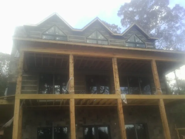 Dormers and porch framing on a large log home under construction — Roof Coating work by our crew in Perry Point