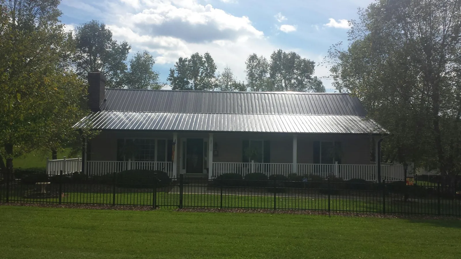 Gray metal roof on a brick ranch with a full width front porch — Gutter Guard Installation work by our crew in Perry Point